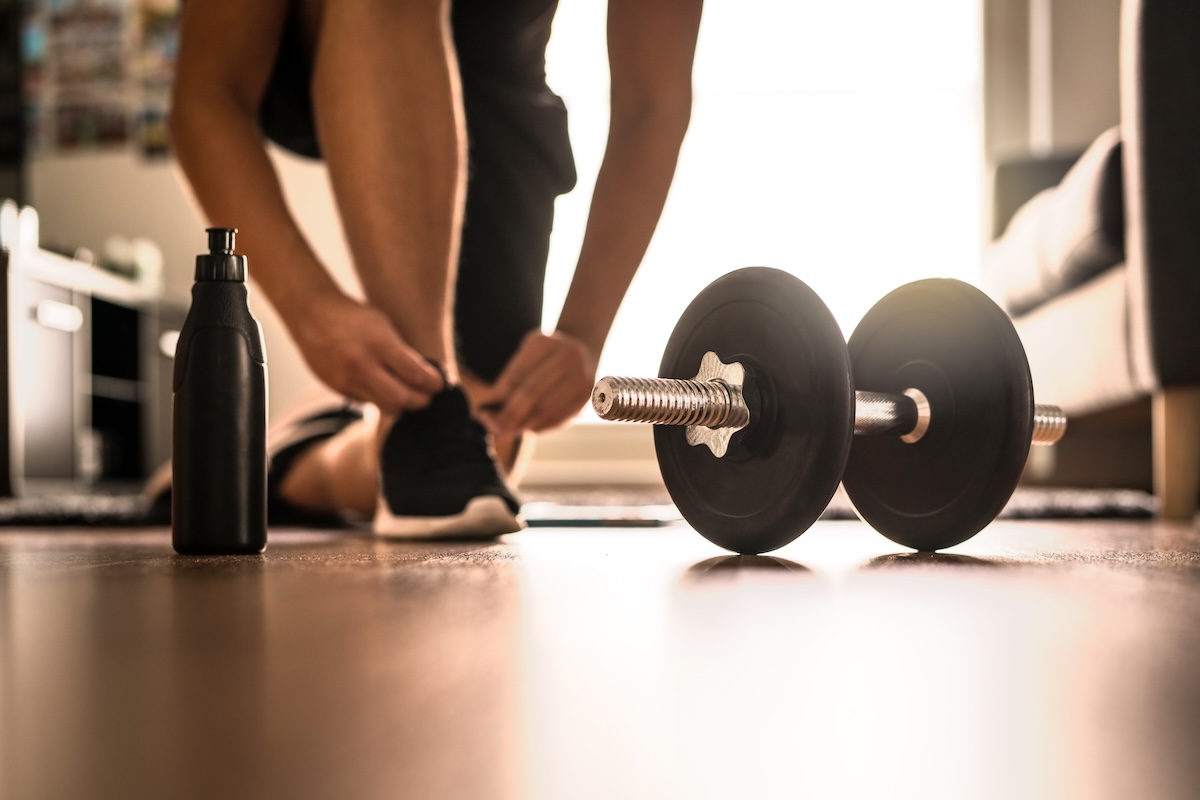 A closeup of a person tying his shoes before engaging in a workout in his home gym with dedicated 15 amp circuit for treadmill. 